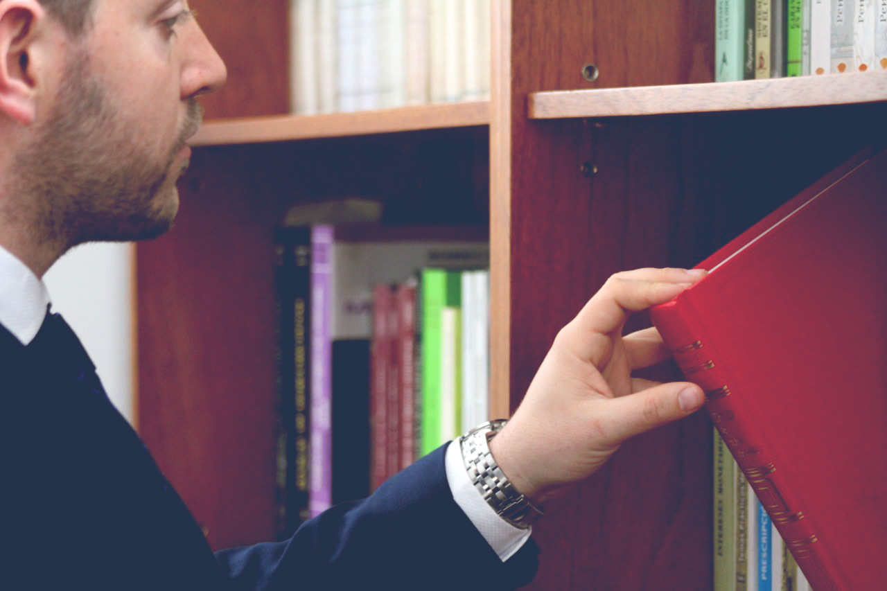 mano sacando un libro rojo de la bibblioteca